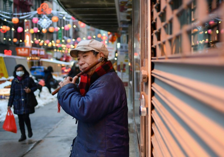 A man plays the flute as people walk through Chinatown in New York City on February 11, 2021