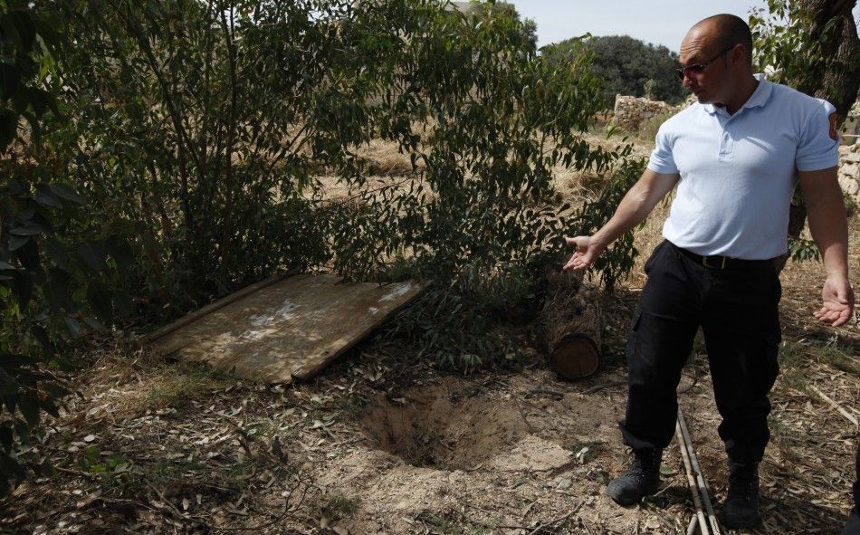 Animal welfare officer shows the hole in the ground where they found a dog buried alive in a field near Birzebbuga in the south of Malta