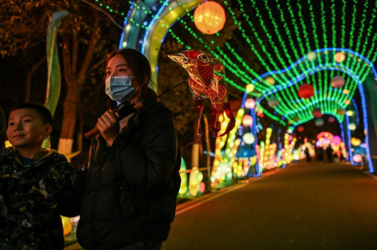 People wear face masks as they walk past lanterns in a park in Wuhan, China ahead of the start of the Lunar New Year, which ushers in the Year of the Ox