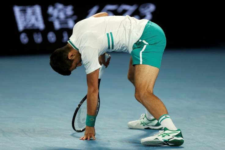 Novak Djokovic is doubled up in pain after stretching for a shot against Milos Raonic