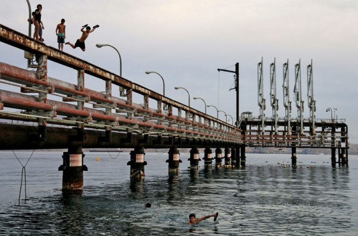 Youths jump into the Red Sea water off an abandoned oil jetty in Israel's southern port city of Eilat