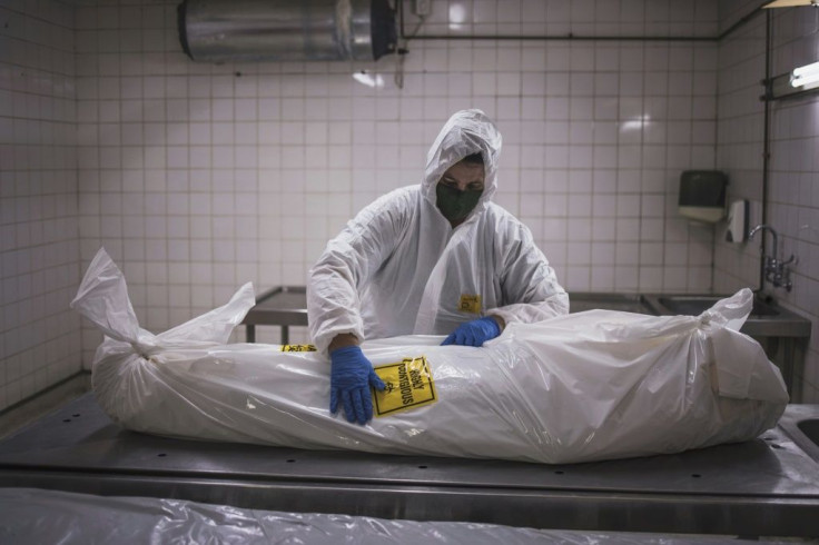 A morgue attendant at the Pretoria branch of the South African funeral and burial services company Avbob applies a biohazard warning on the body of COVID-19 victim