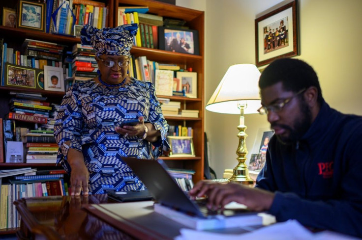 Nigeria's Ngozi Okonjo-Iweala is helped by her son Okechukwu Iweala (R) as she works on her acceptance speech at her home in Potomac, Maryland, near Washington DC