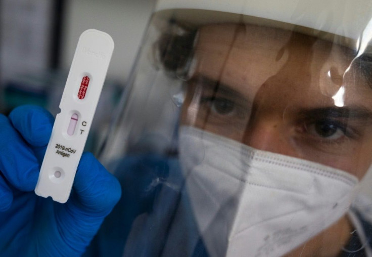 A health professional poses with a test cassette used for an antigen rapid test for Covid-19 at a testing center in Berlin