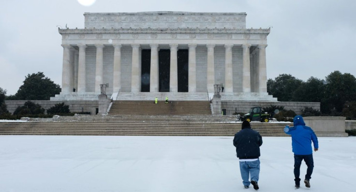 Men are seen outside of the Lincoln Memorial under a blanket of light snow in Washington, DC on February 18, 2021