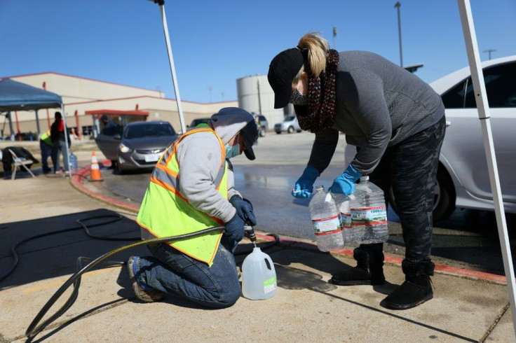 People help fill jugs at a drive-through water distribution center at a high school in Kyle, Texas on February 20, 2021