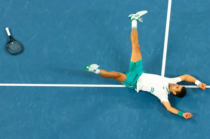 Novak Djokovic drops to the court in celebration after securing match point against Daniil Medvedev