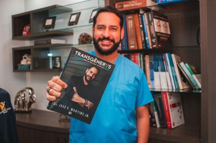 This handout picture released by the Transgender Centre Brazil shows Brazilian doctor Jose Martins posing for a picture as he holds a book about transgender people written by him, in Blumenau, Brazil, on July 8, 2020
