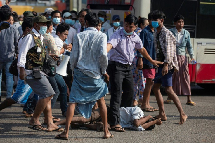 Military supporters stand over a man who was attacked during a rally in Yangon on Thursday