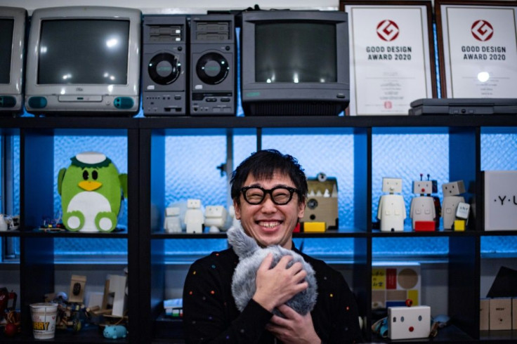 Shunsuke Aoki, CEO of Yukai Engineering, hugs the robotic cushion Qoobo, which has a mechanical tail that wiggles
