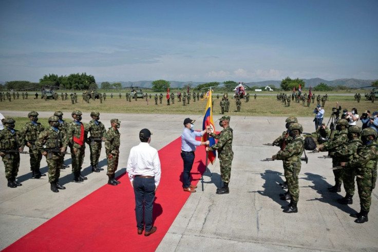 Colombian President Ivan Duque (C-L) handing a Colombian flag to Brigadier General Juan Carlos Correa Consuegra (C-R) during the inauguration of the Command Against Drug Trafficking and Offshore Threats (CONAT) at the Tolemaida base in Cundinamarca depart