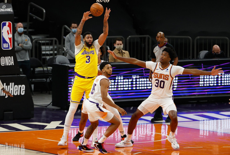 Anthony Davis #3 of the Los Angeles Lakers passes the ball over Cameron Payne #15 and Damian Jones #30 of the Phoenix Suns