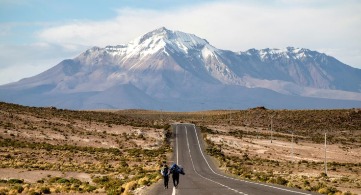 Venezuelan migrants trudge along an exposed road on the altiplano in northern Chile, having crossed the border from Bolivia