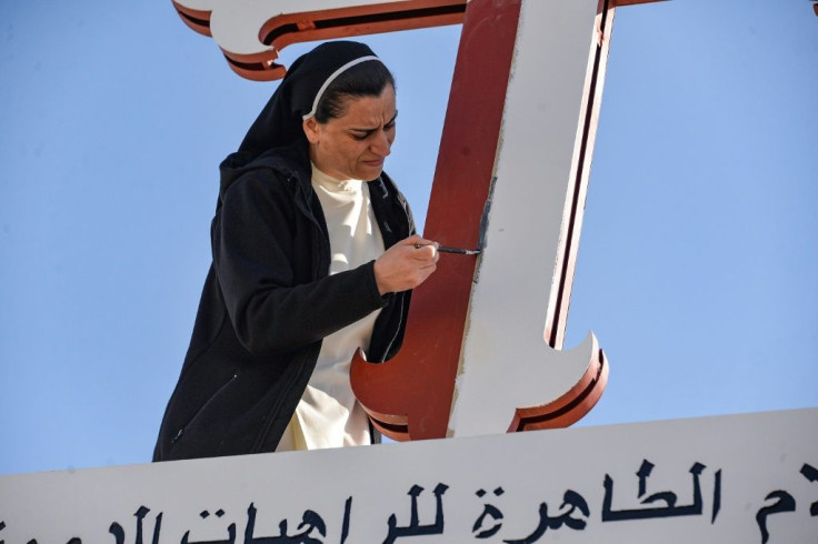 A nun adds a coat of paint to a cross of the Immaculate Mary Dominican Sisters Convent in the predominantly Christian town of Qaraqosh near Mosul