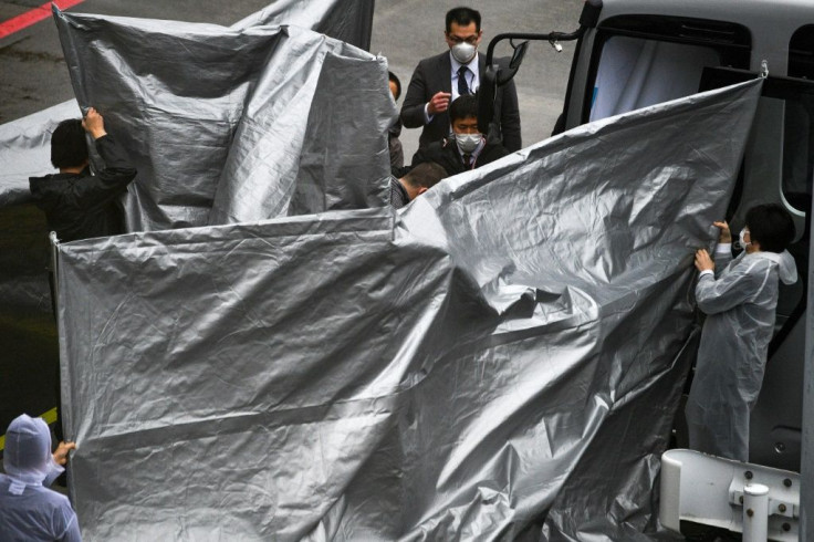 Officials held up silver plastic sheets to shield the arriving Taylors from cameras at Narita airport