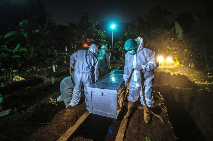 Gravediggers bury a Covid-19 coronavirus victim at a cemetery in Bogor, on the outskirts of Jakarta, Indonesia on March 2, 2021
