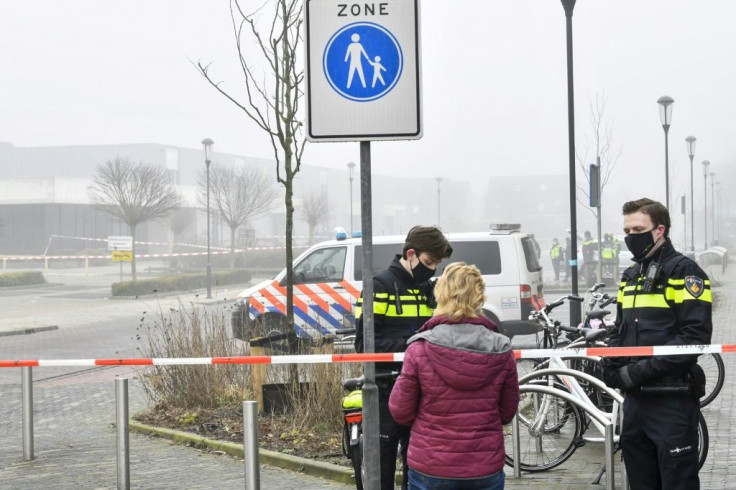Police officers speak with a pedestrian as they close off a street after an explosion occurred near a Covid-19 test centre, shattering windows but causing no apparent injuries, in Bovenkarspel, the Netherlands