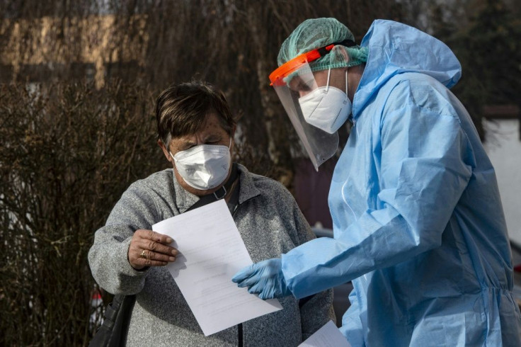 A Czech soldier wearing protective equipment (PPE) shows the results of a coronavirus test to a patient in Chodova Plana town, western Bohemia
