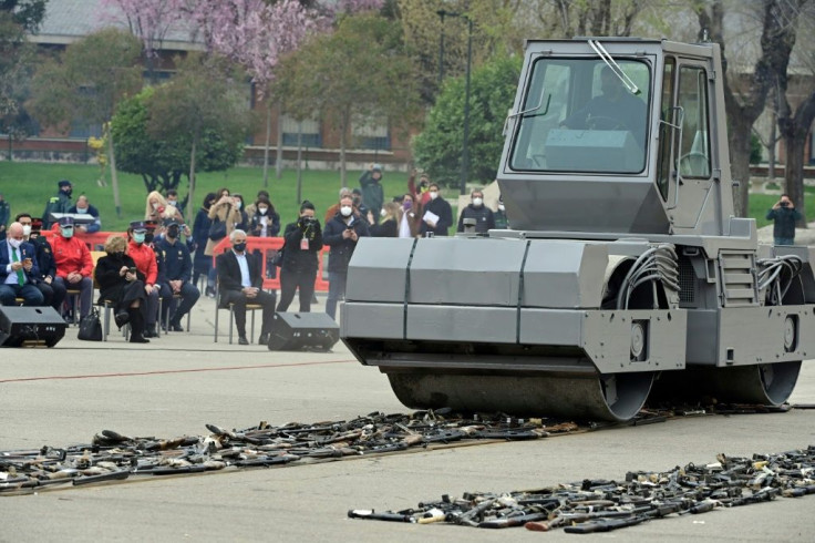 A steamroller slowly drives over three rows of weapons that belonged to Basque separatist group ETA
