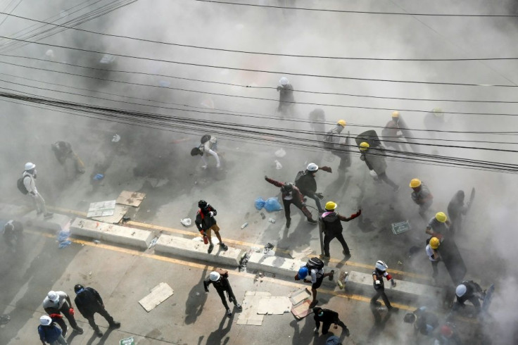 Protesters react after tear gas was fired by security forces in an attempt to disperse them during a demonstration against the military coup in Yangon on March 4, 2021