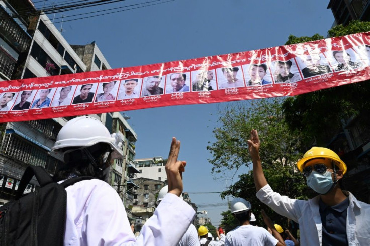 Medical personnel and students held up the three finger salute below a row of portraits of people who died from security forces gun fire on Friday