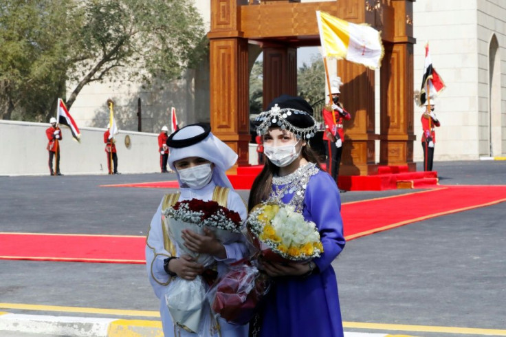 Iraqi children wearing traditional Arab and Kurdish dress wait for the pope's arrival at the presidential palace in Baghdad's fortified Green Zone
