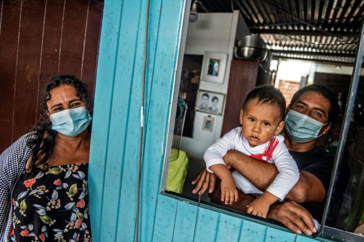 Nancy Sanchez, 48, poses with her husband Narciso and her grandchild at their home