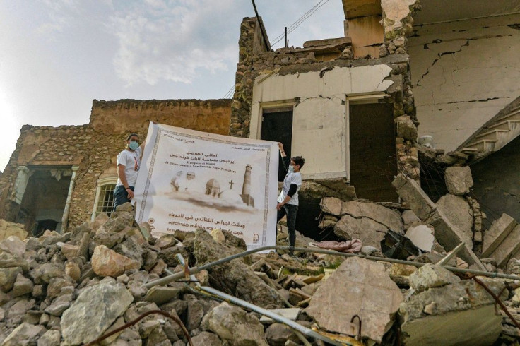 Youths unfurled a poster welcoming Francis next to the ruins of the Syriac Catholic Church of the Immaculate Conception in Mosul