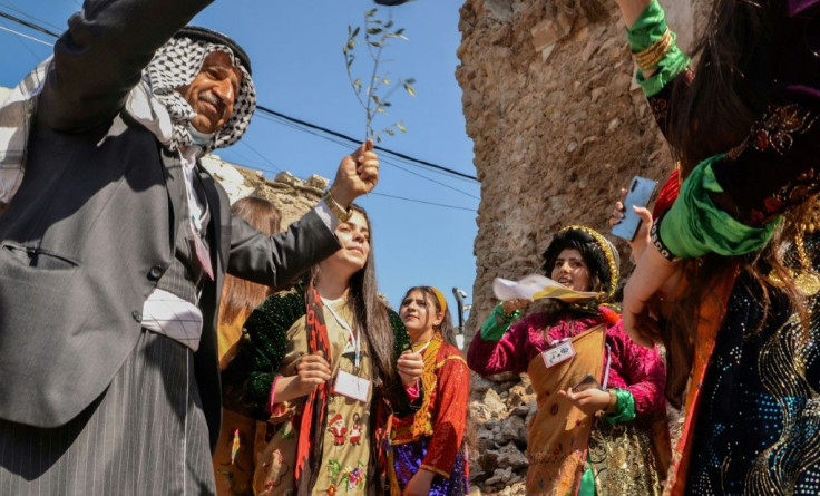 Young women dressed in traditional clothing celebrate the arrival of Pope Francis in Mosul's old city