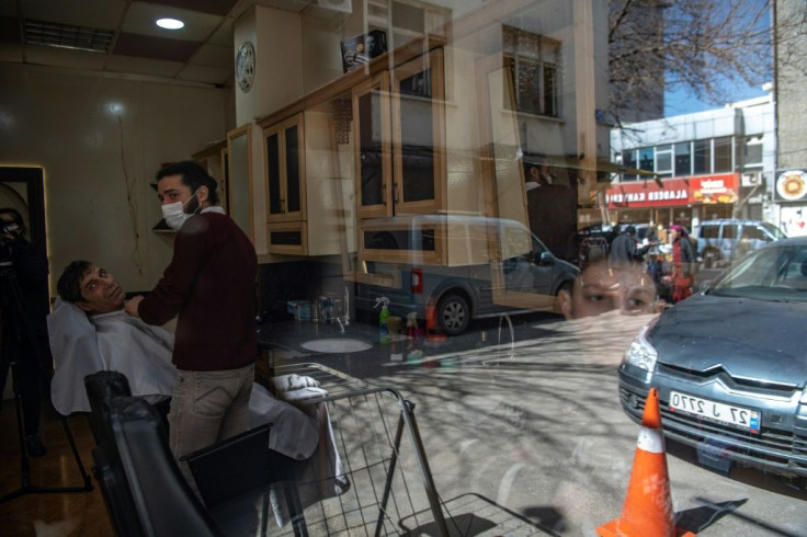 In his barbershop, Mohammad Abu Al-Nar, 28, and his customers discuss their native Syria's fate