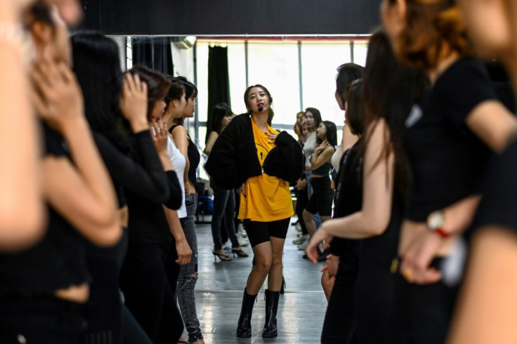 Instructor Pham Kieu Ly (C) demonstrates a pose to participants during a course teaching them how to pose for photographs on their mobile phones at a studio in Hanoi