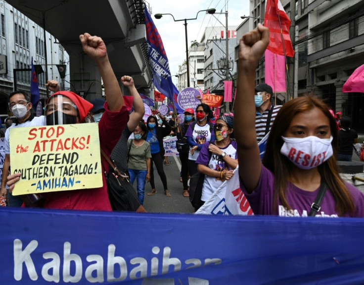Following the anti-communist raids, a member of women's group Gabriela holds a placard that reads "Stop the Attacks!" during a march towards the presidential palace on International Women's Day in Manila