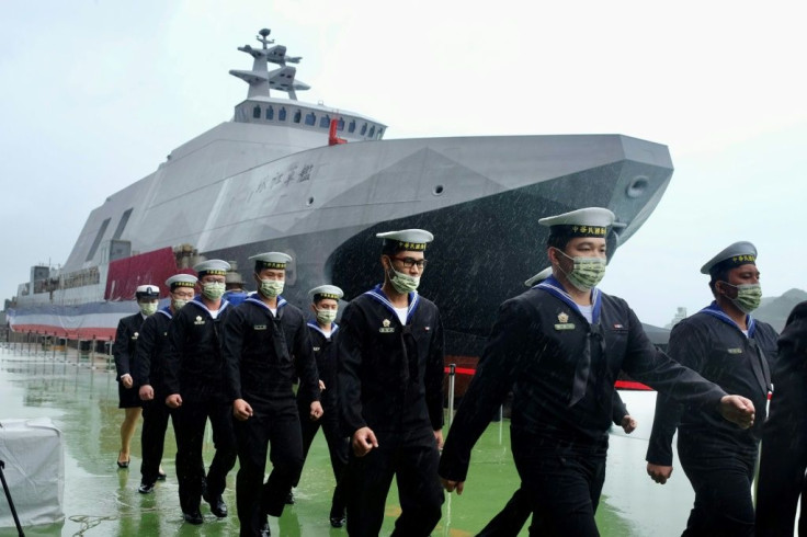 Navy sailors walk past a ship in Taiwain, which faces a constant threat of invasion by China