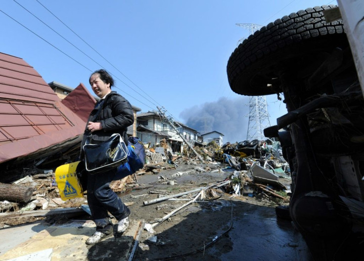 A local resident collects his son's school bags from a collapsed house in Miyagi prefecture