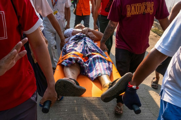 People carry an injured resident, who was shot with rubber bullets as security force destroyed barricades erected by protesters against the military coup, in Yangon on March 9, 2021