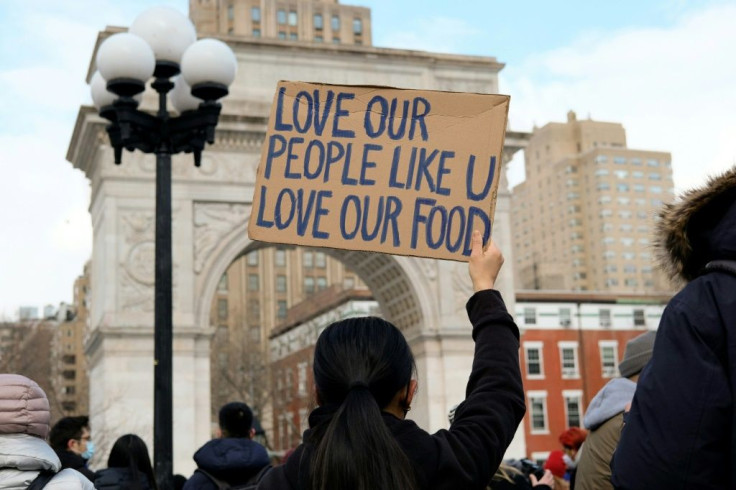 A woman holds a sign that reads "Love our people like u love our food" at the End The Violence Towards Asians rally in Washington Square Park on February 20, 2021 in New York City