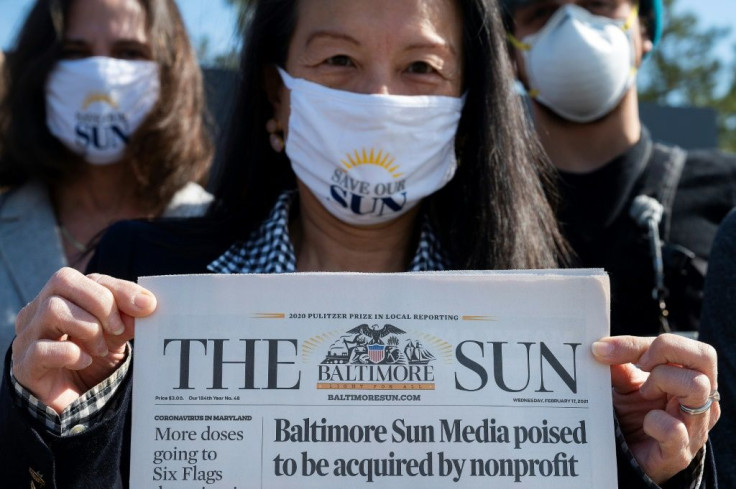 Baltimore Sun reporter Jean Marbella holds up the newspaper's front page that headlined its potential take over by a nonprofit group during an interview on March 11