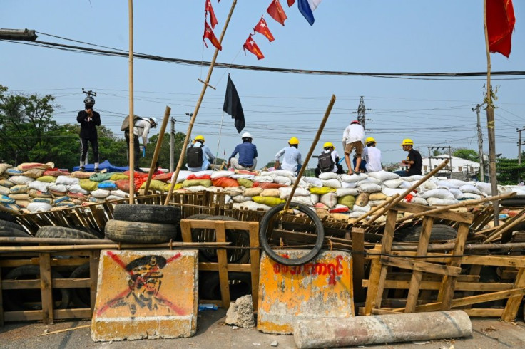 Protesters sit on a makeshift barricade erected to deter security forces in Yangon