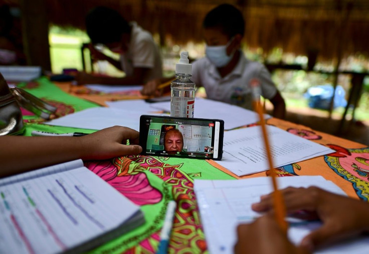 The teacher uses her mobile phone to record the children's English practice, which she sends to a colleague via WhatsApp for evaluation