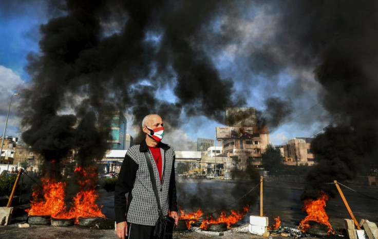 Lebanese protesters angry at the failure of politicians and bankers to halt the slide in their standard of living block a road outside Beirut