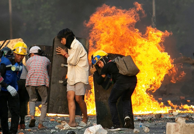 Protesters take cover behind homemade shields as they confront security forces