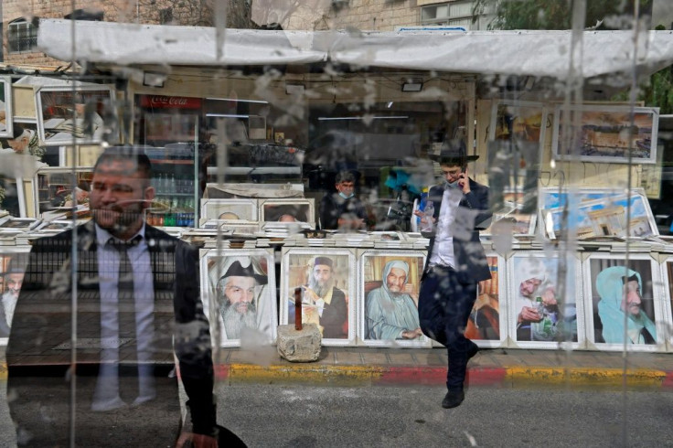 People walk past a street stall selling portraits of Jewish rabbi leaders in an ultra-Orthodox Jewish neighbourhood in Jerusalem, on March 11, 2021