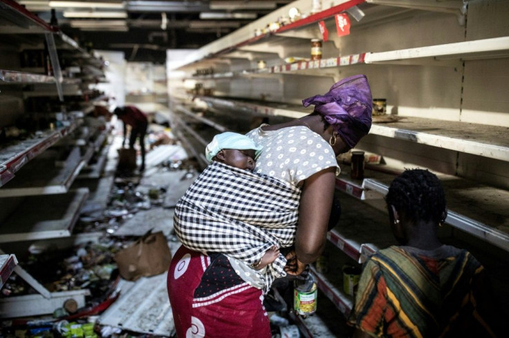 A woman picks up groceries at a looted supermarket in Dakar on March 6. The store was one of several owned by France's Auchan chain which were torched and pillaged during the unrest