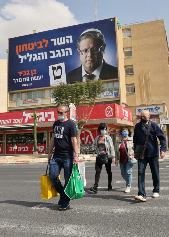 Israelis pass a campaign poster for Ben-Gvir in the city of Beersheba this week