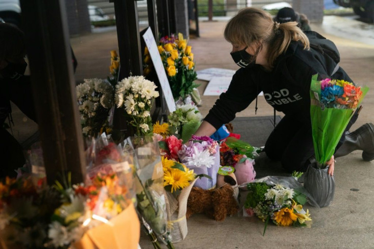 Shelby Swan adjusts flowers and signs outside Youngs Asian Massage where four people were shot and killed in Acworth, Georgia