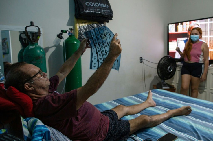 Jessica Vitoria da Silva Oliveira (R), 22, looks at her father Josimauro da Silva, 57, checking his X-ray at their home in Manaus
