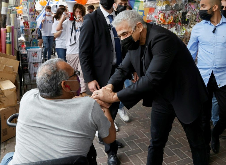 Israeli opposition leader Yair Lapid presses the flesh in the coastal city of Hod Hasharon, taking advantage of the country's world-beating coronavirus vaccination campaign to make a final face-to-face push for votes