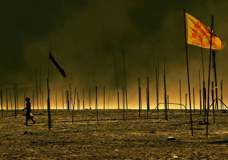 In this photo taken in the early morning of April 13, 2020 a woman walks past flag poles marking where beach kiosks renting chairs and selling drinks would normally be, on Copacabana beach, in Rio de Janeiro, Brazil amid the coronavirus pandemic