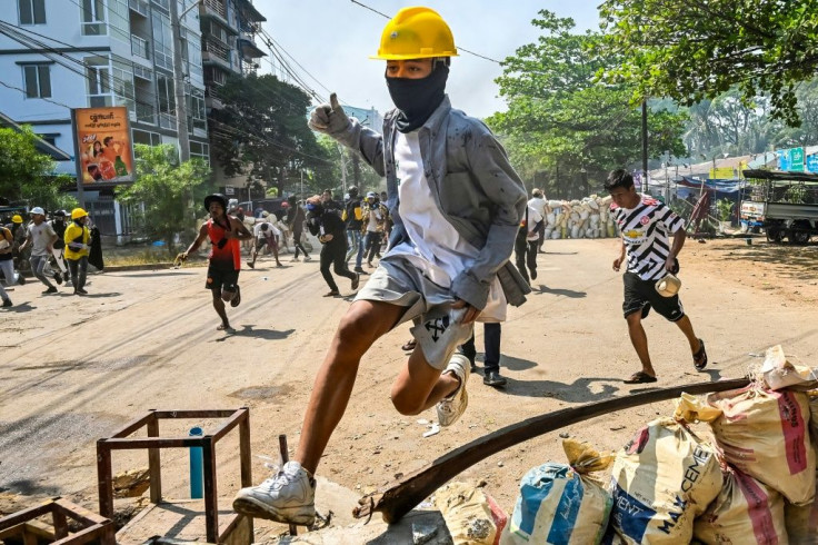 A protester jumps over a makeshift barricade as security forces crack down on a demonstration in Yangon's Thaketa township on March 19, 2021