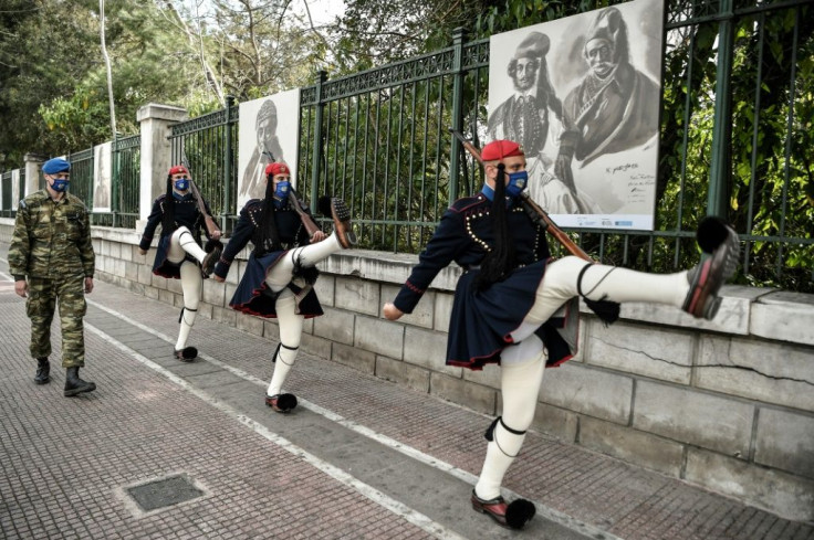 Greek presidental guards march past the outdoor exhibition featuring portraits of revolution heroes